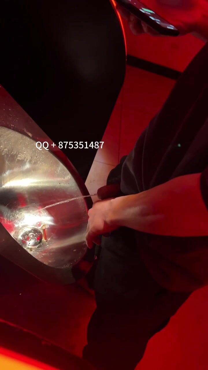 A male is pissing in the toilet.