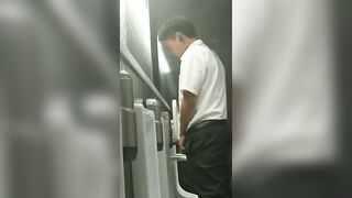 A male is pissing in the toilet.