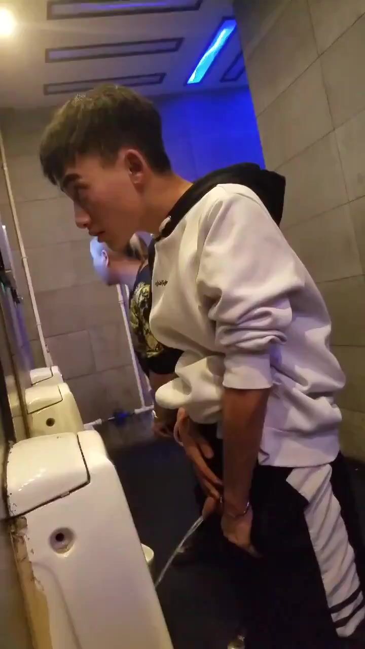 A male is pissing in the toilet.