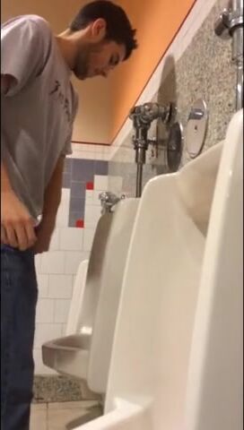 A male is pissing in the toilet.