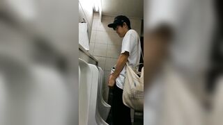 A male is pissing in the toilet.