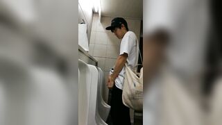 A male is pissing in the toilet.