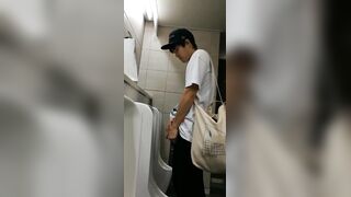 A male is pissing in the toilet.