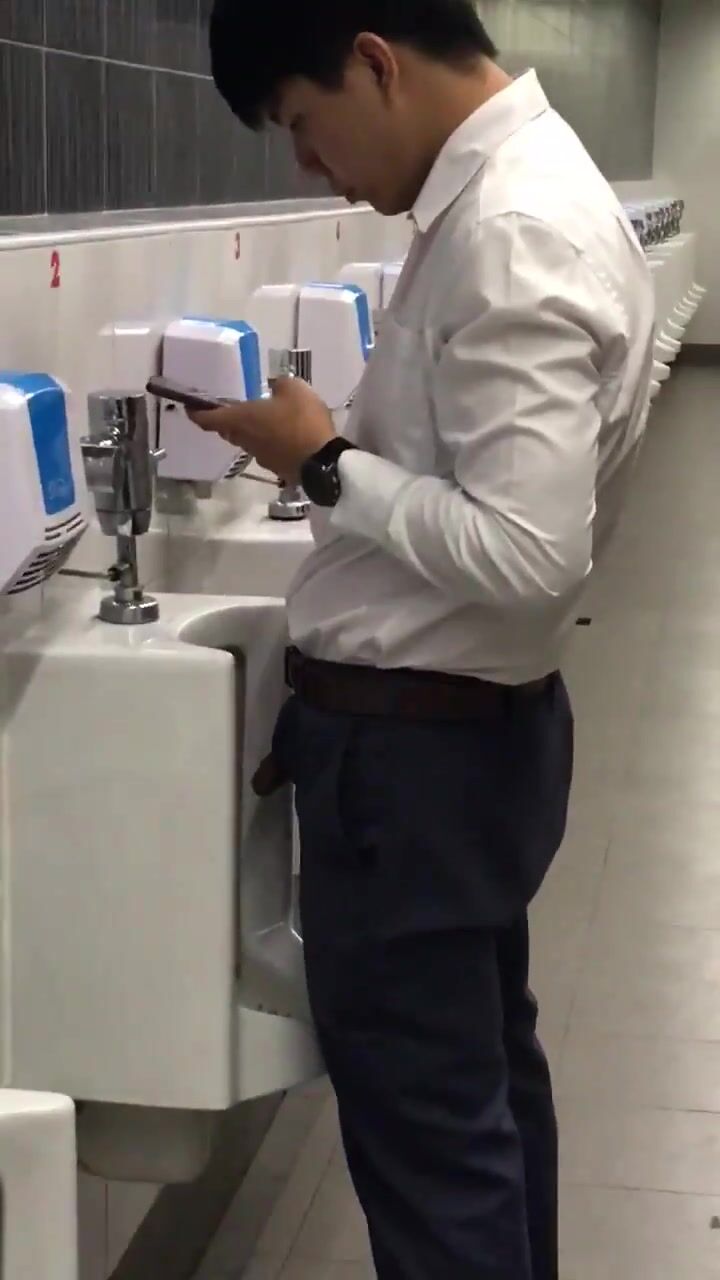 A male is pissing in the toilet.