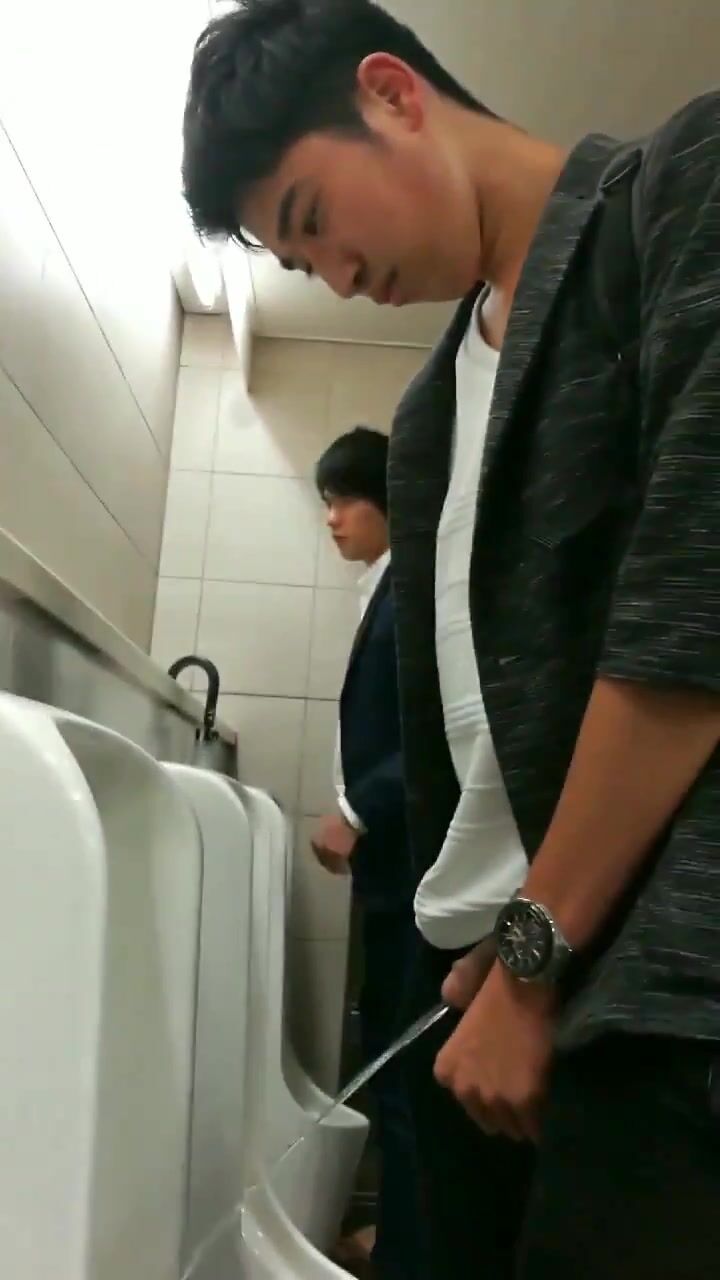 A male is pissing in the toilet.
