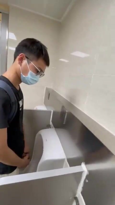 A male is pissing in the toilet.