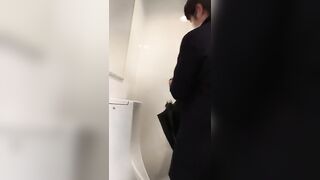 A male is pissing in the toilet.
