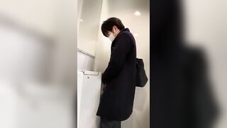 A male is pissing in the toilet.