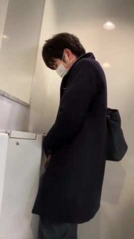A male is pissing in the toilet.