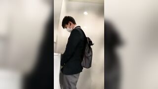 A male student is pissing in the toilet.