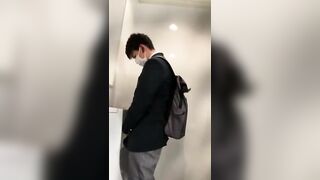 A male student is pissing in the toilet.