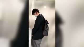A male student is pissing in the toilet.