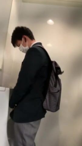 A male student is pissing in the toilet.