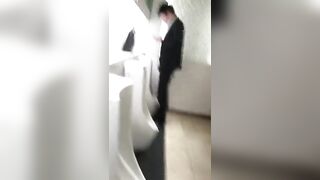 A male is pissing in the toilet.