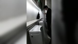 A male is pissing in the toilet.