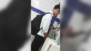 A male is pissing in the toilet.