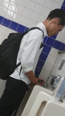 A male is pissing in the toilet.