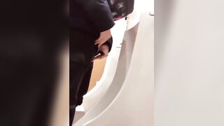 A male is pissing in the toilet.