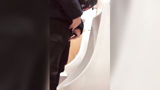 A male is pissing in the toilet.