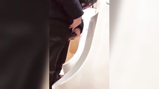A male is pissing in the toilet.