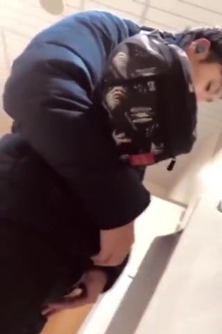 A male is pissing in the toilet.