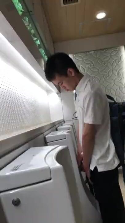 A male student is pissing in the toilet.