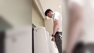 A male is pissing in the toilet.