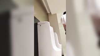 A male is pissing in the toilet.
