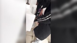 A handsome male student is pissing in the toilet.