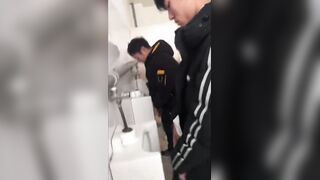 A handsome male student is pissing in the toilet.