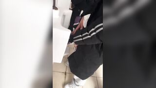 A handsome male student is pissing in the toilet.