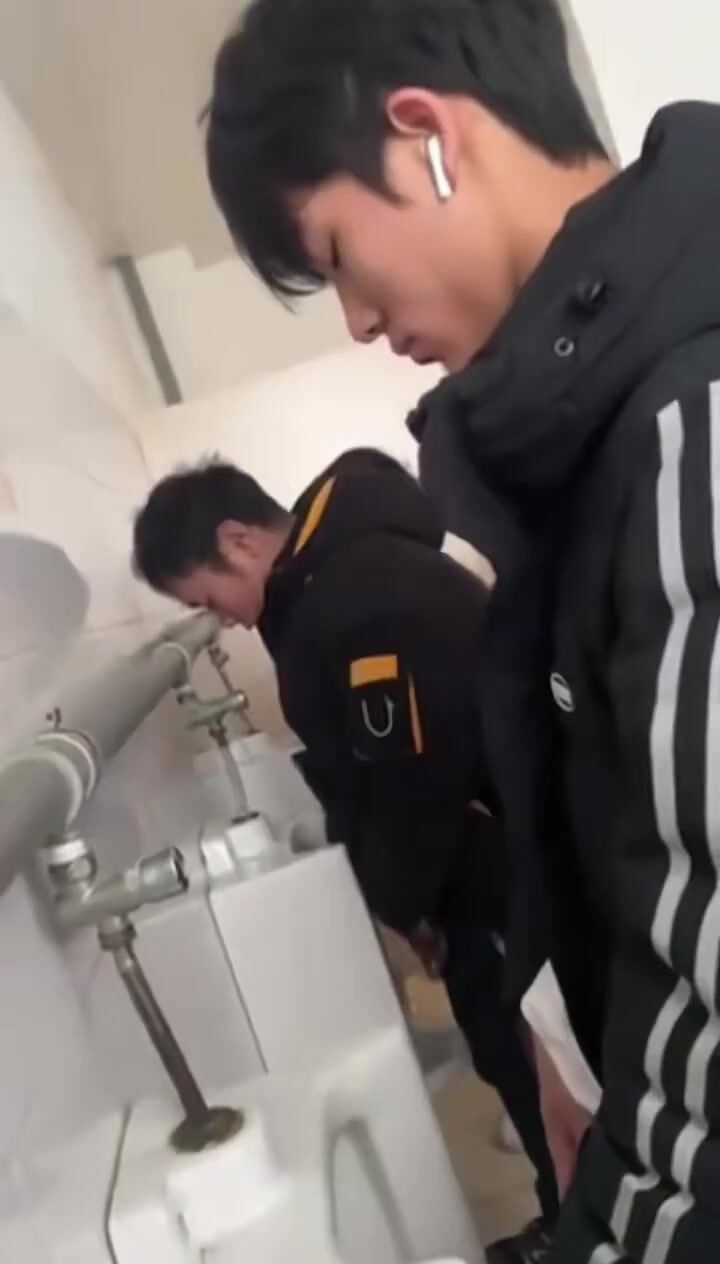 A handsome male student is pissing in the toilet.