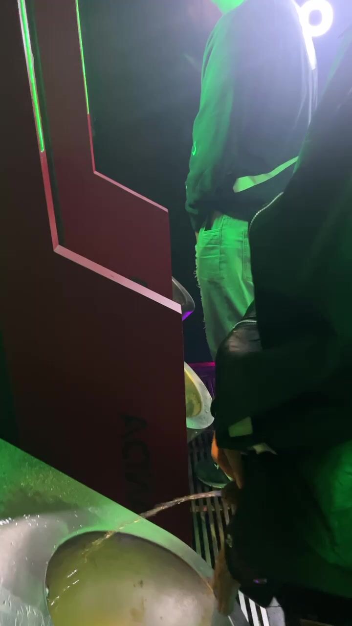 A handsome boy is pissing in the toilet.