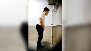 A male is pissing in the toilet.