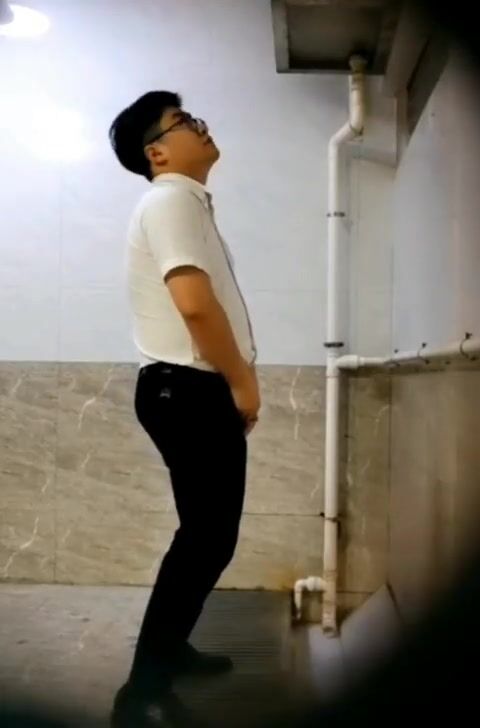 A male is pissing in the toilet.