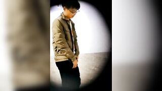 A male is pissing in the toilet.