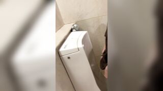 A male is pissing in the toilet.