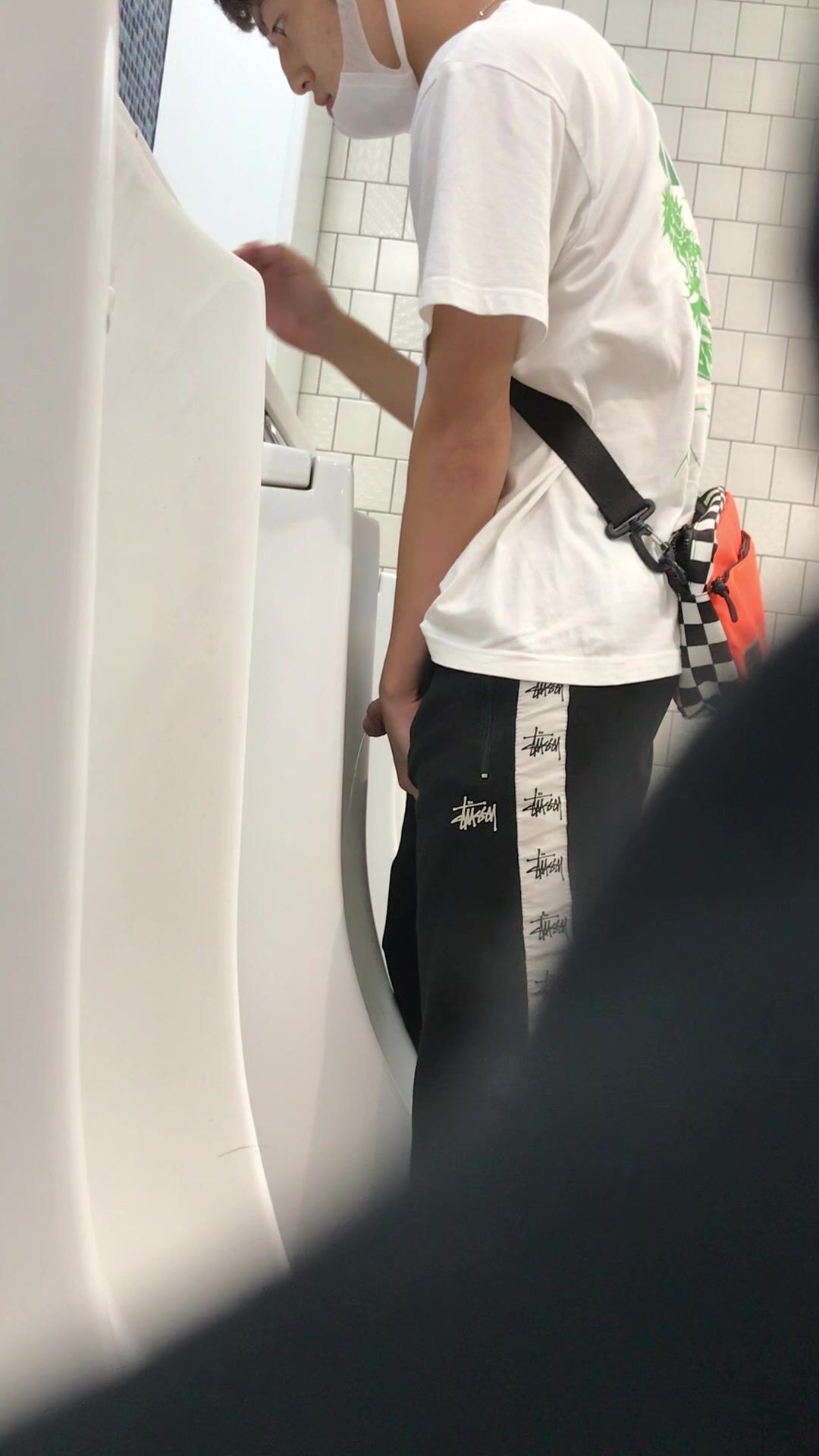 A male is pissing in the toilet.