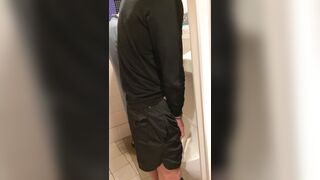 A male is pissing in the toilet.