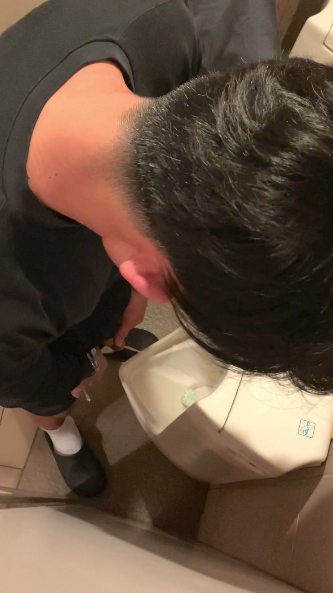 A male is pissing in the toilet.