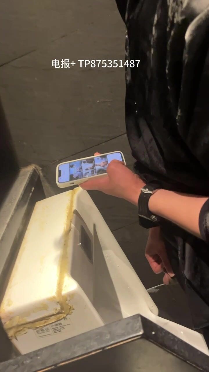 A male is pissing in the toilet.