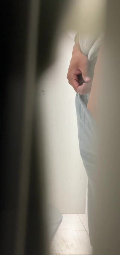 A male is pissing in the toilet.