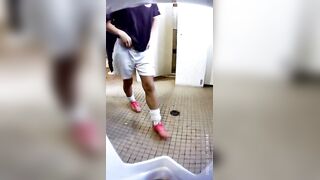 A male student is pissing in the toilet.