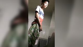 A male is pissing in the toilet.