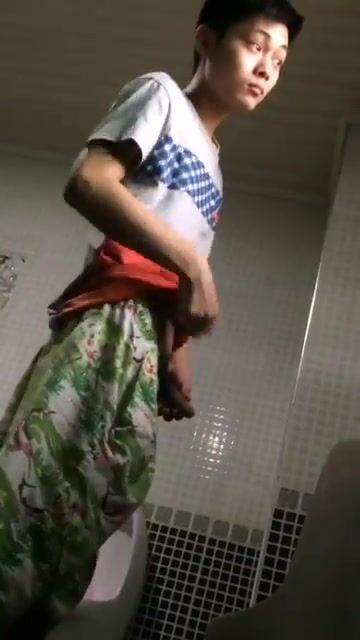 A male is pissing in the toilet.