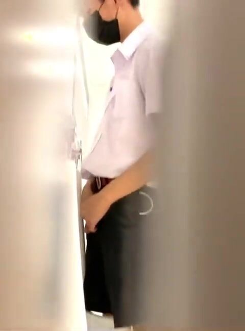 A male is pissing in the toilet.